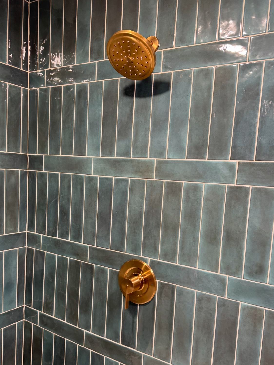 Teal tile shower with brass rain head